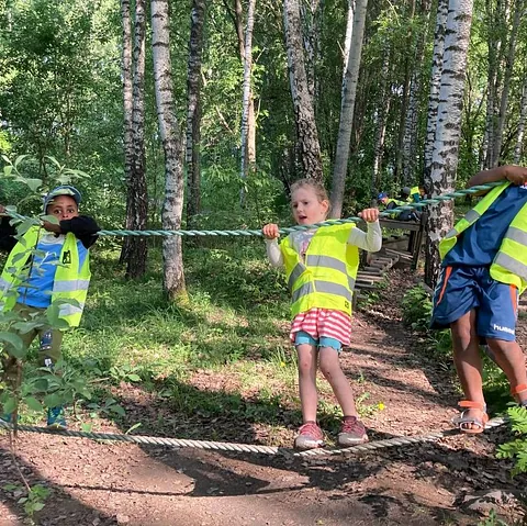 Barn balanserer på tau i skog