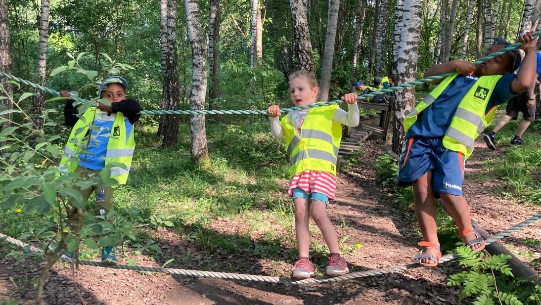 Barn balanserer på tau i skog